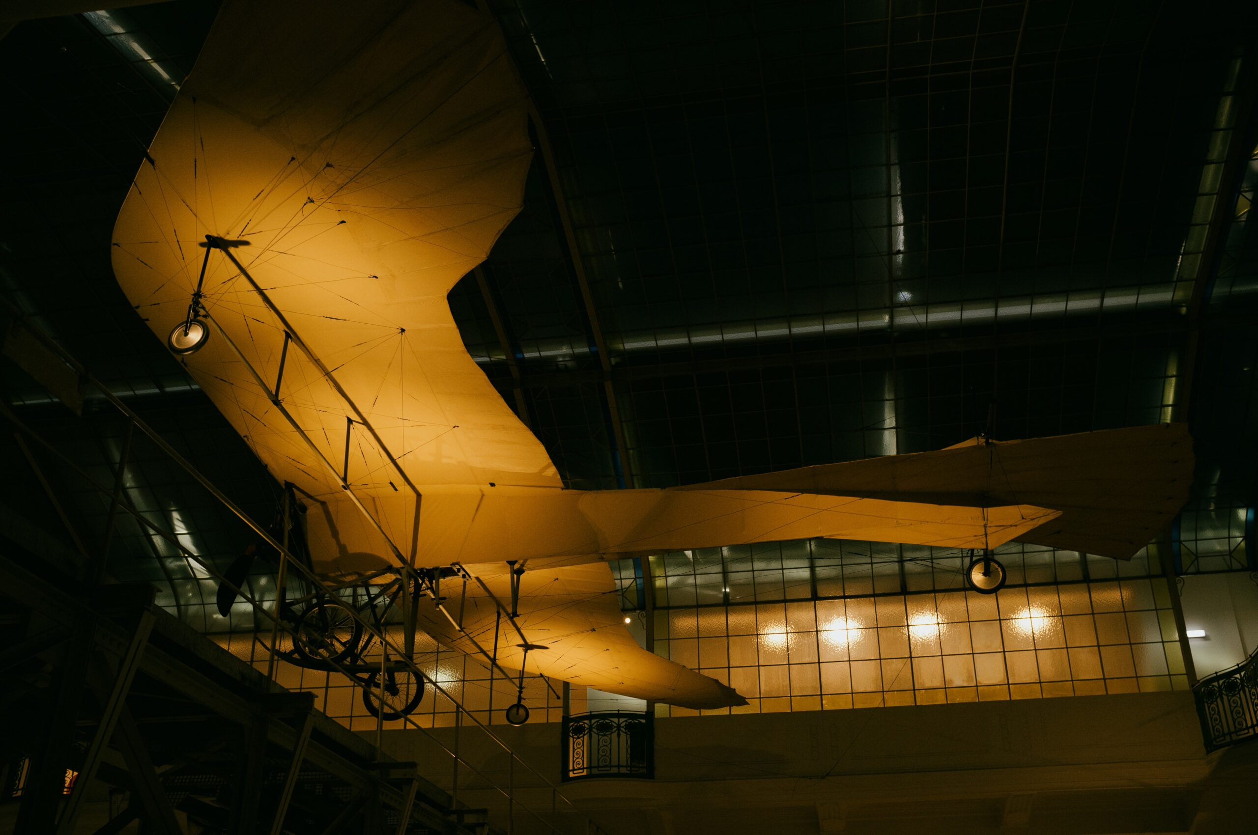 Ein altes Flugzeug welches in einem hohen Raum aufgehängt ist und welches orange beleuchtet ist.