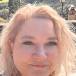 Eine Frau mit blondem Haar blickt direkt in die Kamera