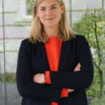 Eine Frau in orangefarbenem Oberteil posiert für ein Foto